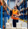 Lagerarbeiter mit Scanner kontrolliert Pakete und Warenregale zur Unterstützung von Logistik, Versand und Bestandsmanagement.