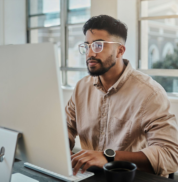 a man with glasses working on a computer