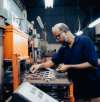 Mitarbeiter arbeitet an einer Industriemaschine und verwaltet produktbezogene Änderungen in der Fertigung.